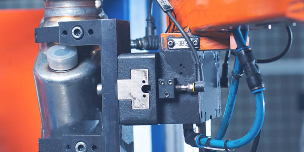 Ein Roboterarm, der ein Werkstück aus Metall hält.