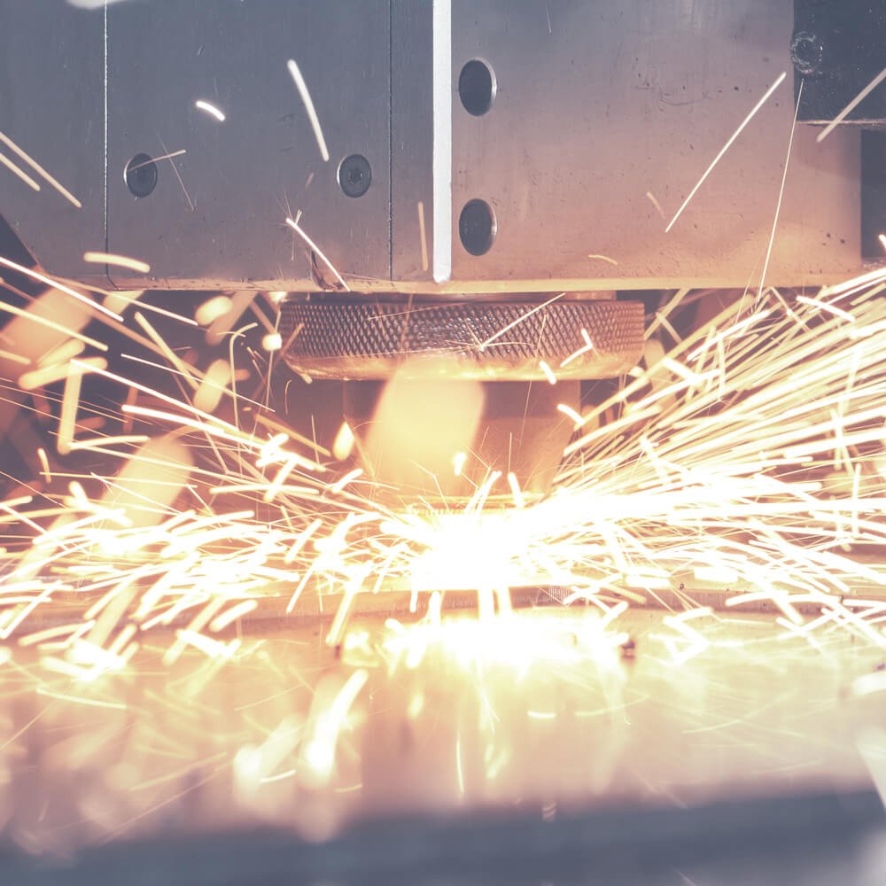 Detailansicht eines Laserstrahl der auf Metall trifft und Funken sprüht.