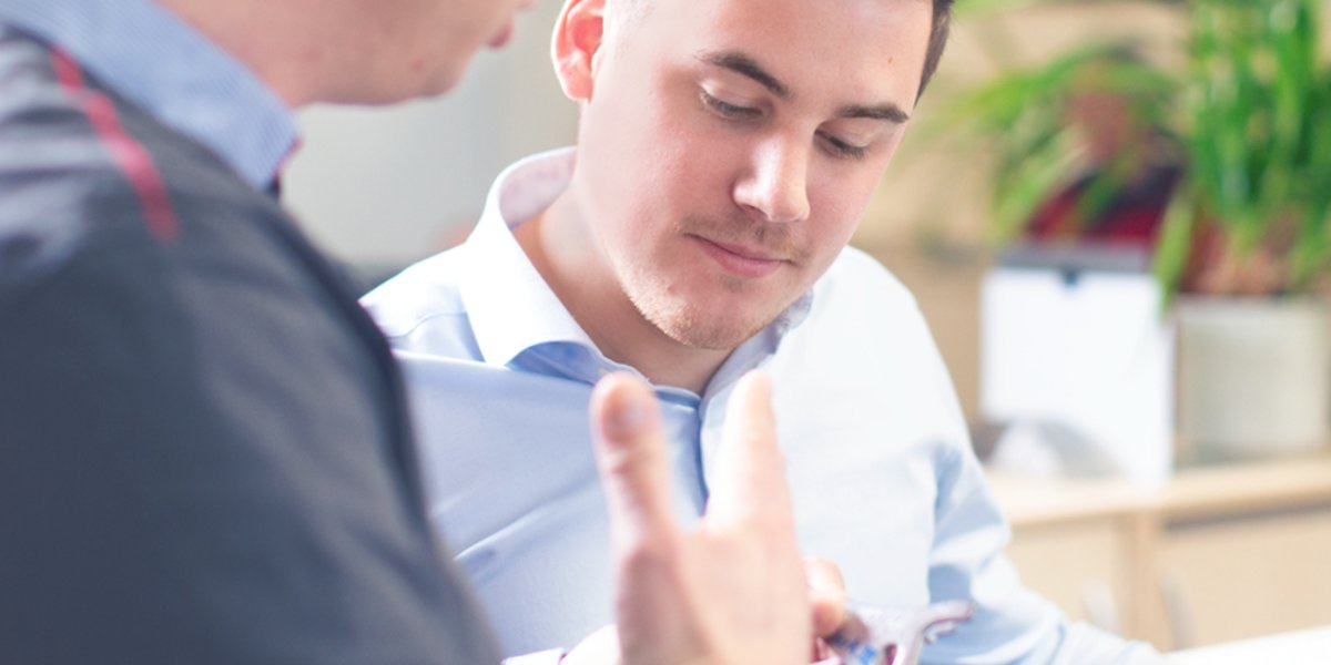 A man looks at a piece of metal that someone else is holding.