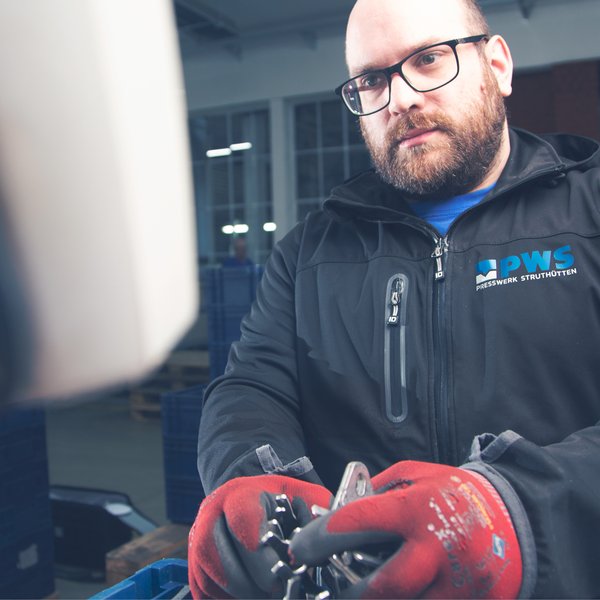 Ein Mann hält eine Werkstück aus Metall.
