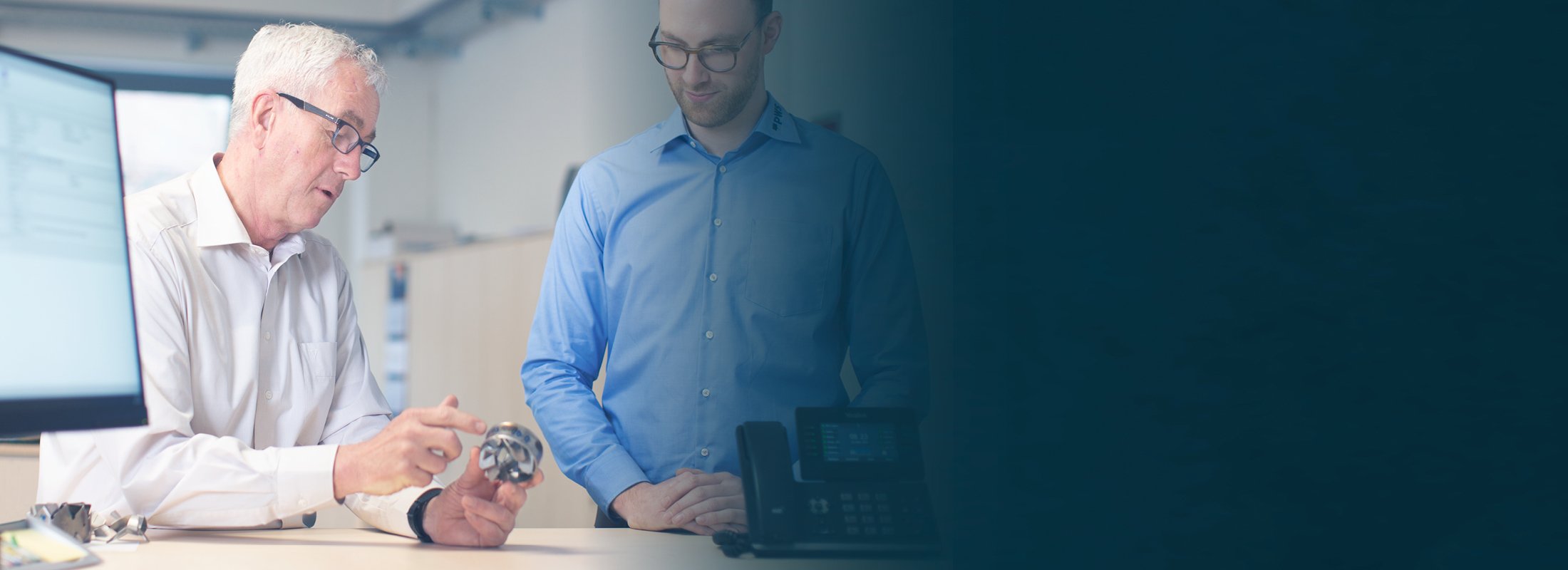 Two men are looking at a piece of metal that one of them is holding.