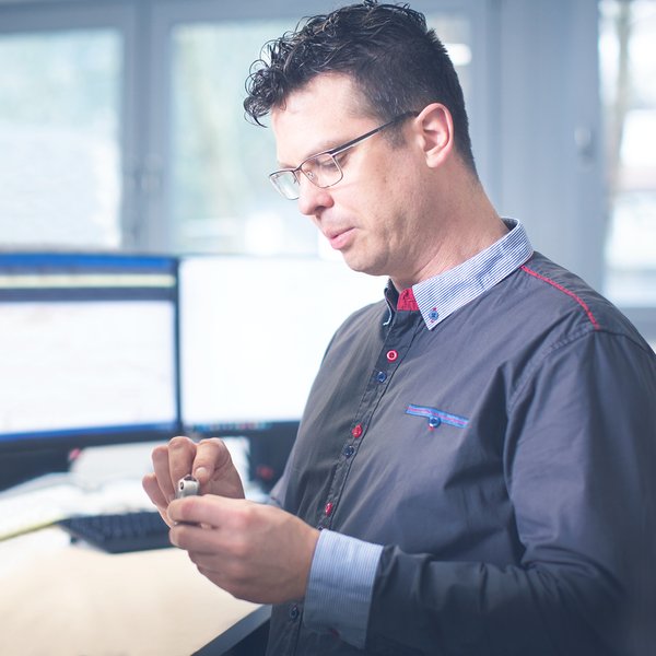 a man looks at a piece of metal that he holds in his hands.