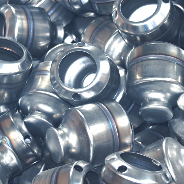 Mehrere identische Werkstücke aus Metall auf einem Haufen.